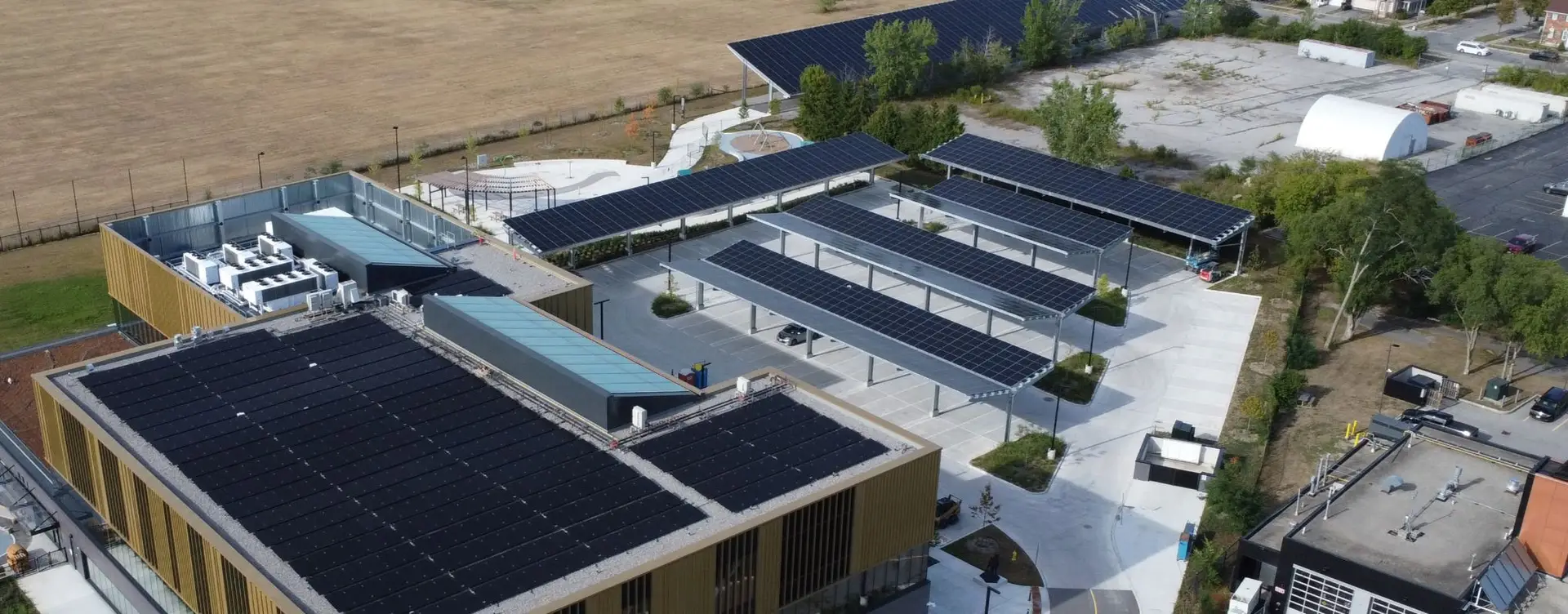 Aerial view of a solar-powered campus building complex with rooftop solar arrays and shaded parking canopies.