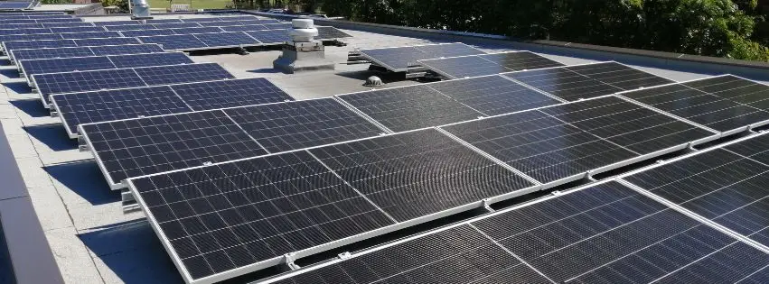 Solar panels on a roof, angled rows shimmering in sunlight.