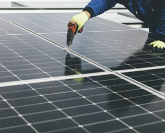 A worker using a screwdriver on a row of solar panels.